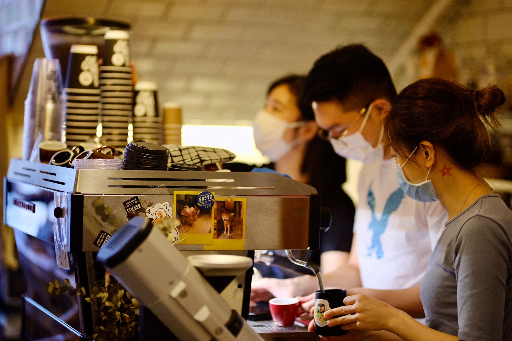Baristas preparing coffee behind the espresso machine at Black Sugar’s Ho Man Tin café.