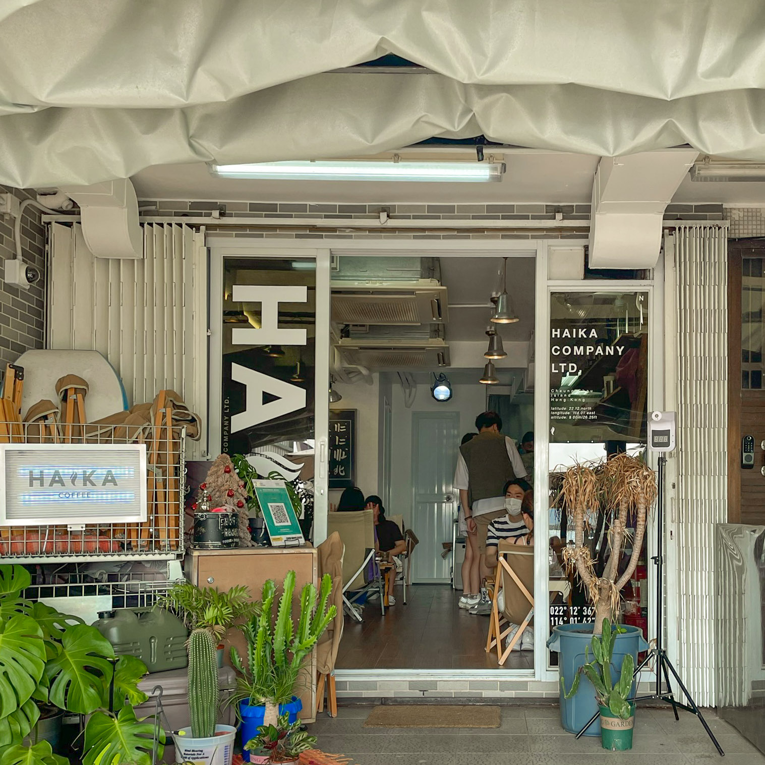HAIKA Coffee entrance in Cheung Chau, with camping chairs, plants, and HAIKA signs.
