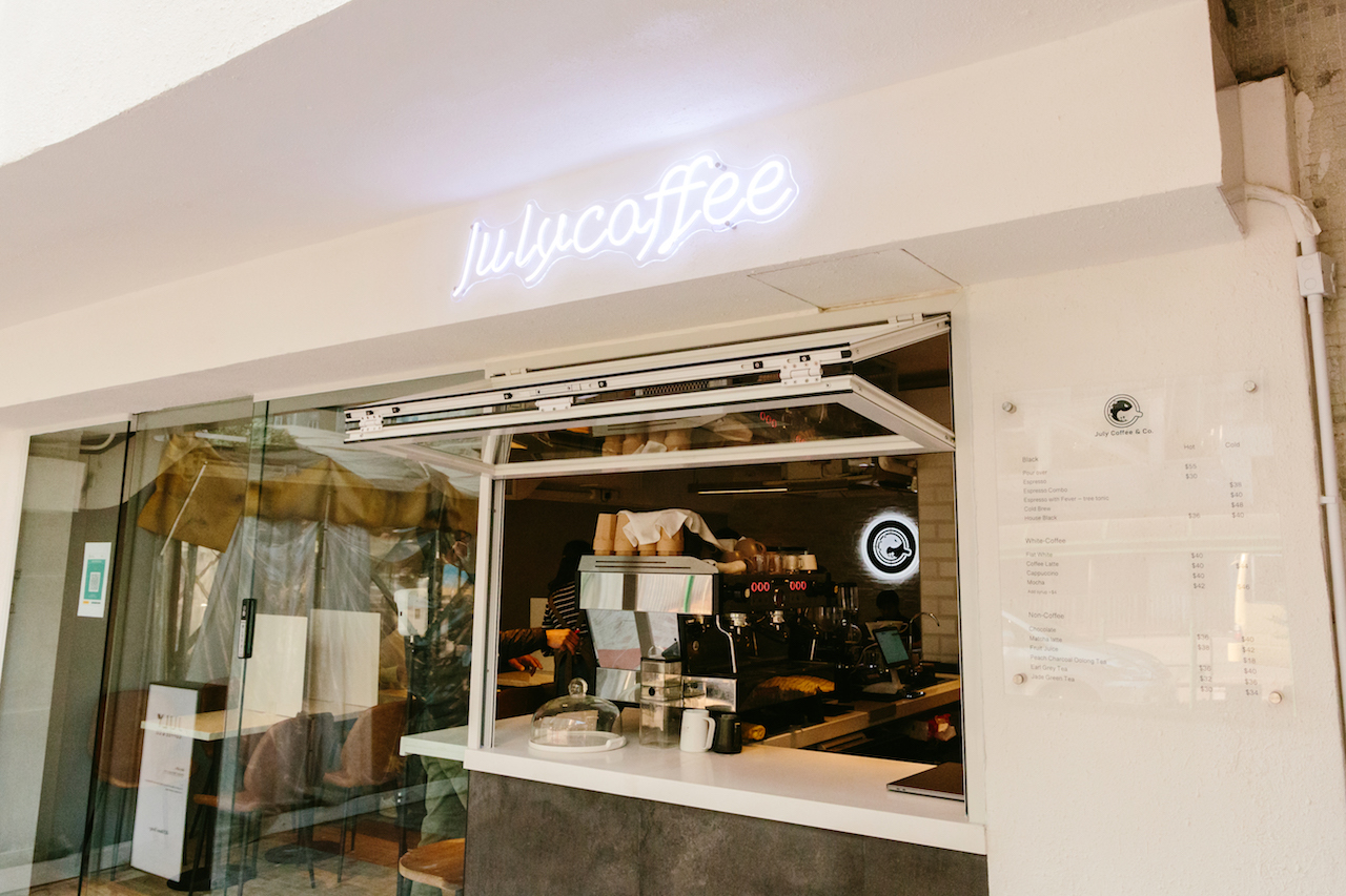 July Coffee & Co. storefront in Sham Tseng, with an illuminated Julycoffee sign, open service window, espresso counter, and glass entrance.
