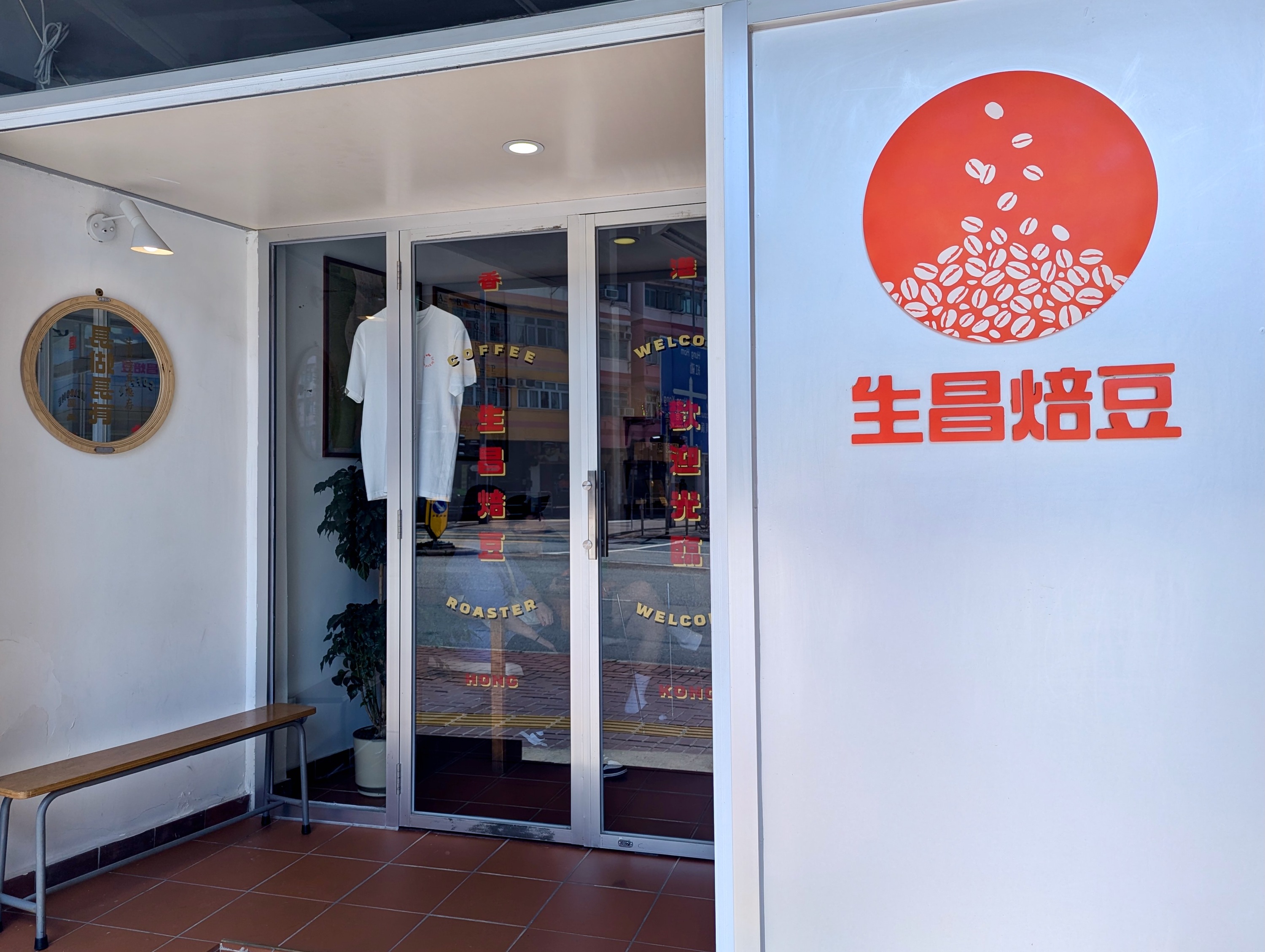 Sang Roastery storefront in To Kwa Wan, with red Chinese signage, glass double doors and a wooden bench.
