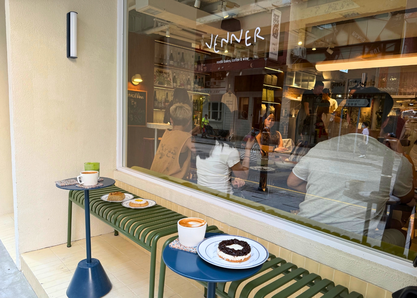Venner’s Hollywood Road window with its current white Venner logo, green outdoor bench and blue café tables.