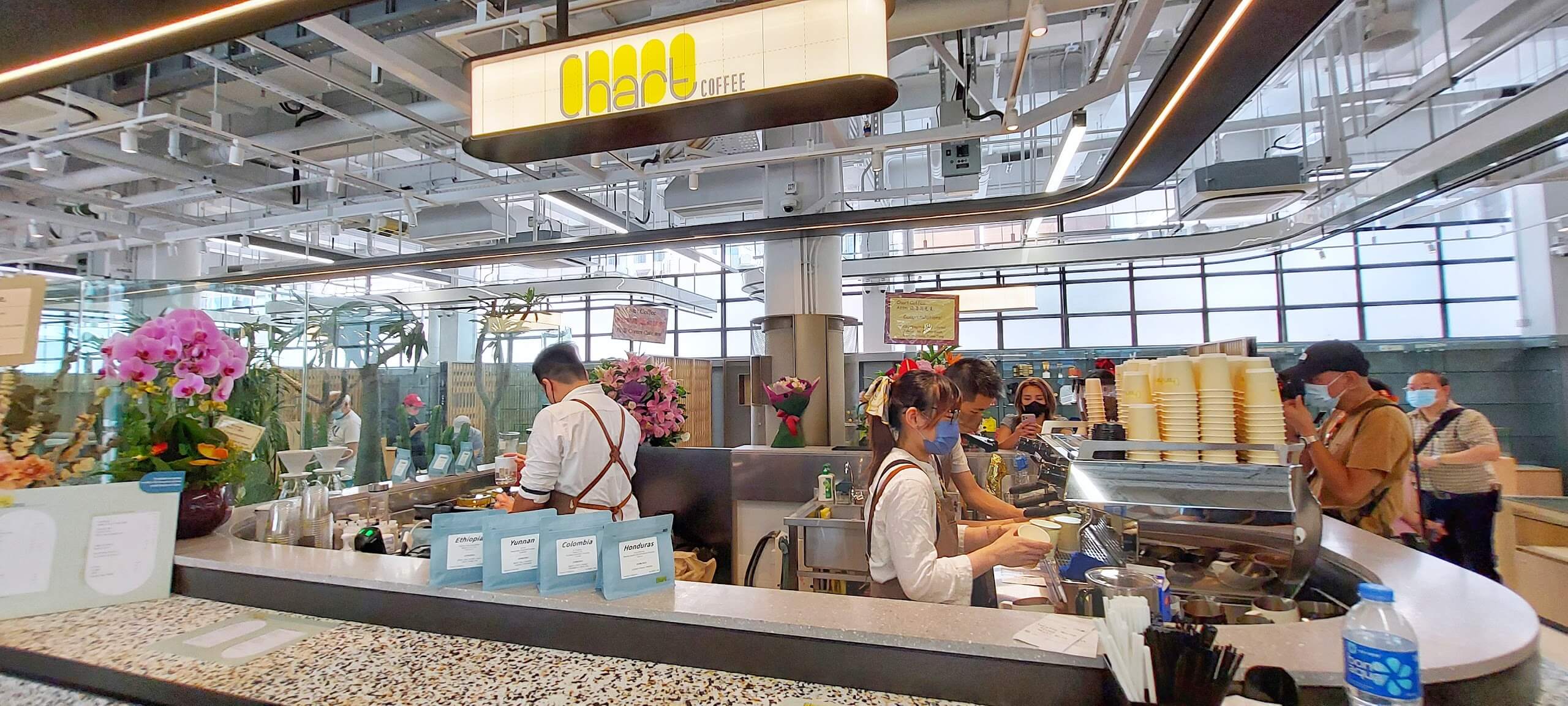 Baristas prepare coffee at Chart’s terrazzo counter beneath its yellow sign in Central Market.