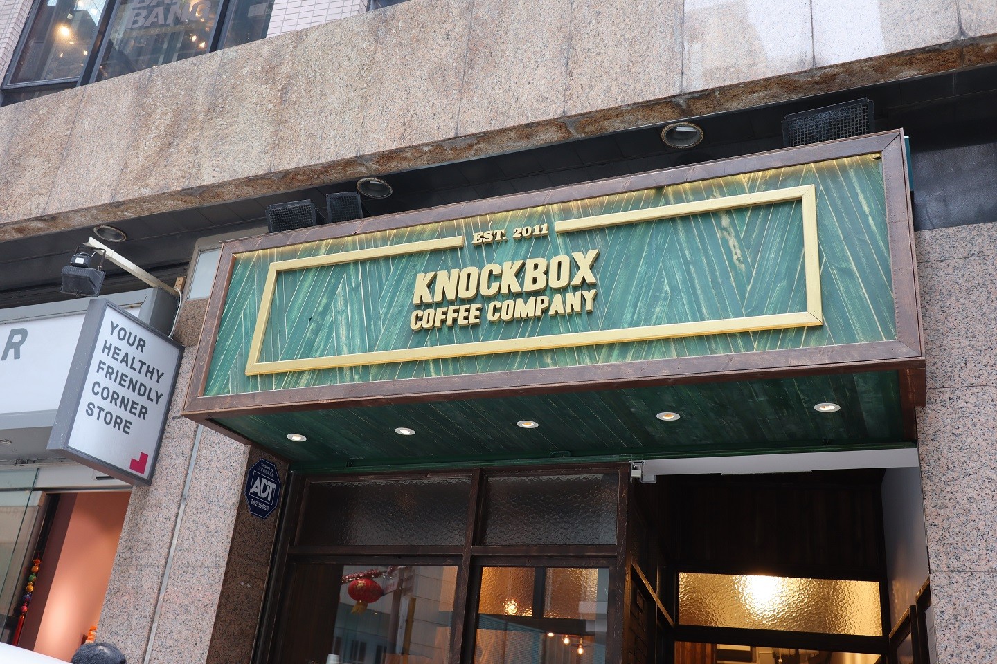 Knockbox Coffee Company’s dark green storefront and gold lettering on Stanley Street.