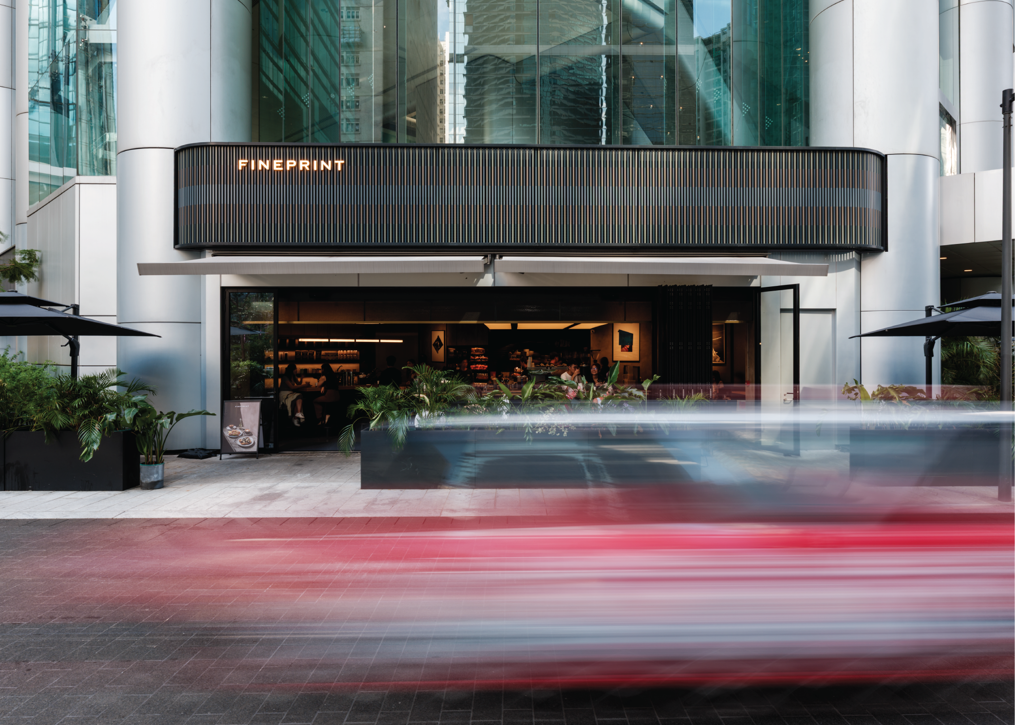 FINEPRINT Quarry Bay storefront with outdoor plants and a passing red taxi