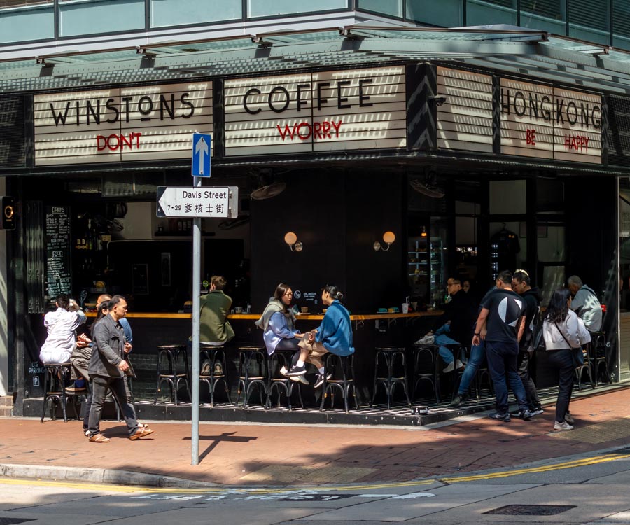 Outdoor seating at Winstons on Davis Street beneath a sign reading Don’t Worry Be Happy.