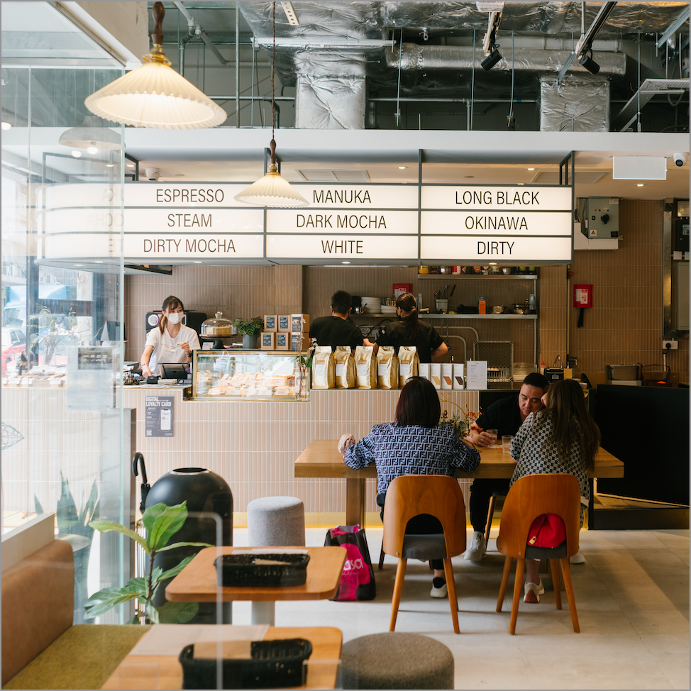 Seating and the illuminated espresso menu inside The Coffee Academïcs at WorFu.