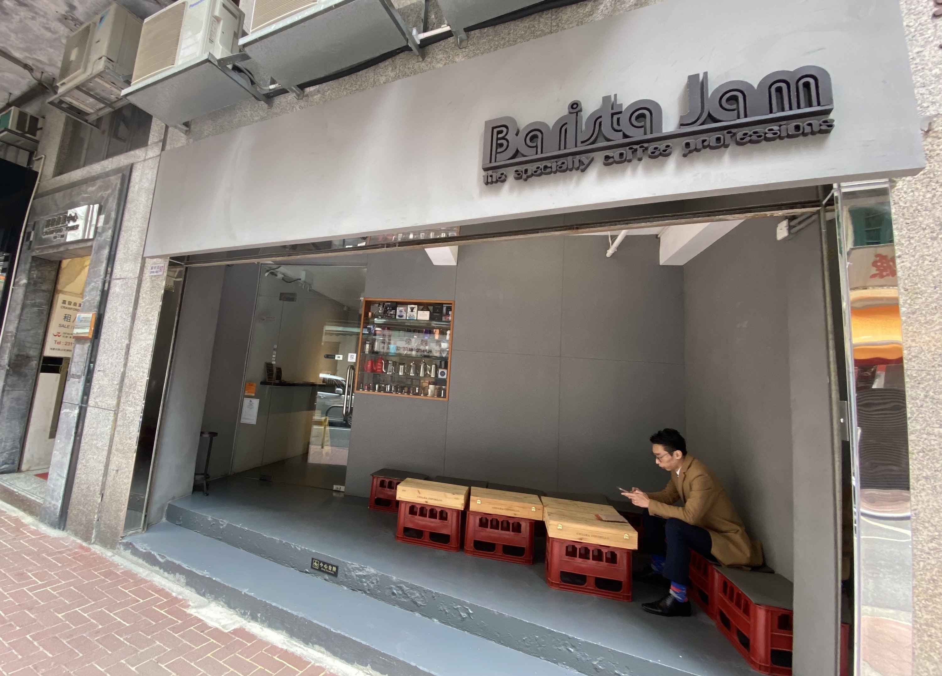 Barista Jam’s grey storefront on Jervois Street, with seating beside the entrance.