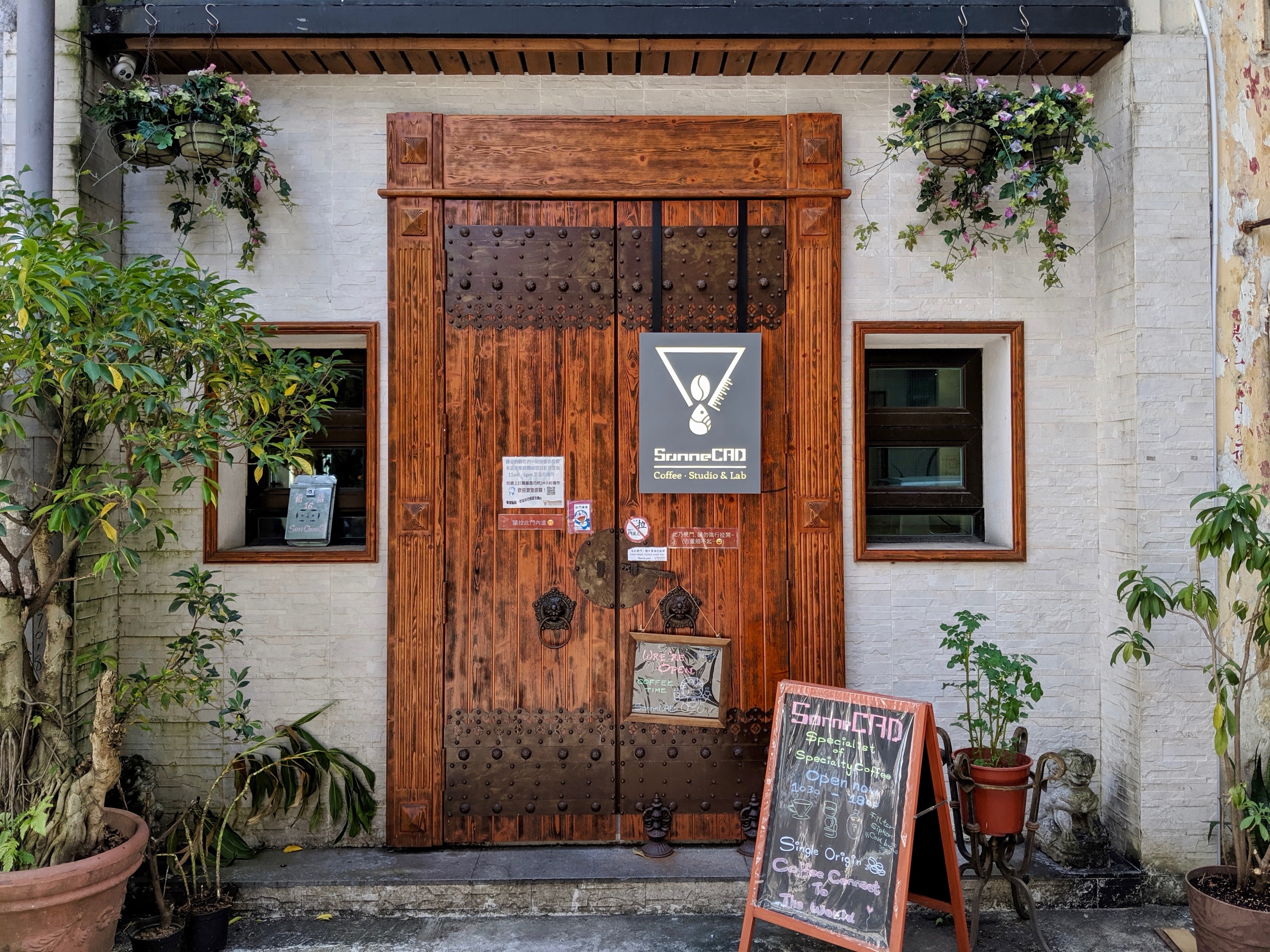Sonne CAD’s wooden entrance and vintage windows surrounded by plants on Sun Chun Street.